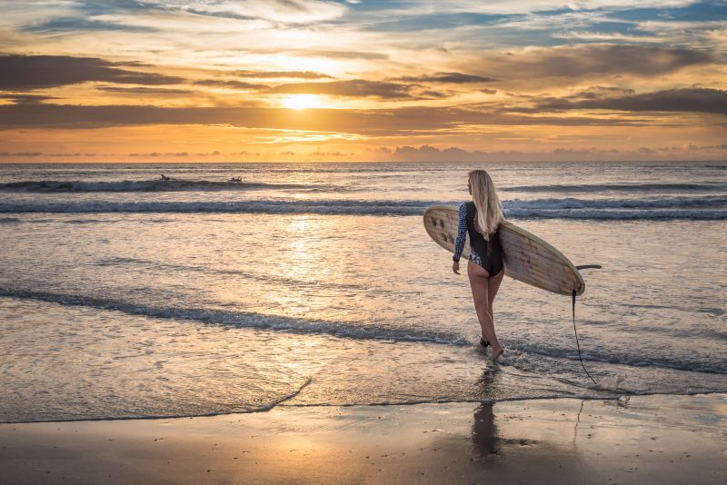 Woman with a surfboard at sunset