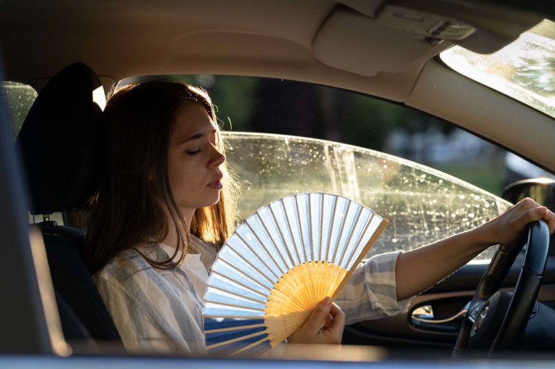 Woman trying to cool down in a hot car